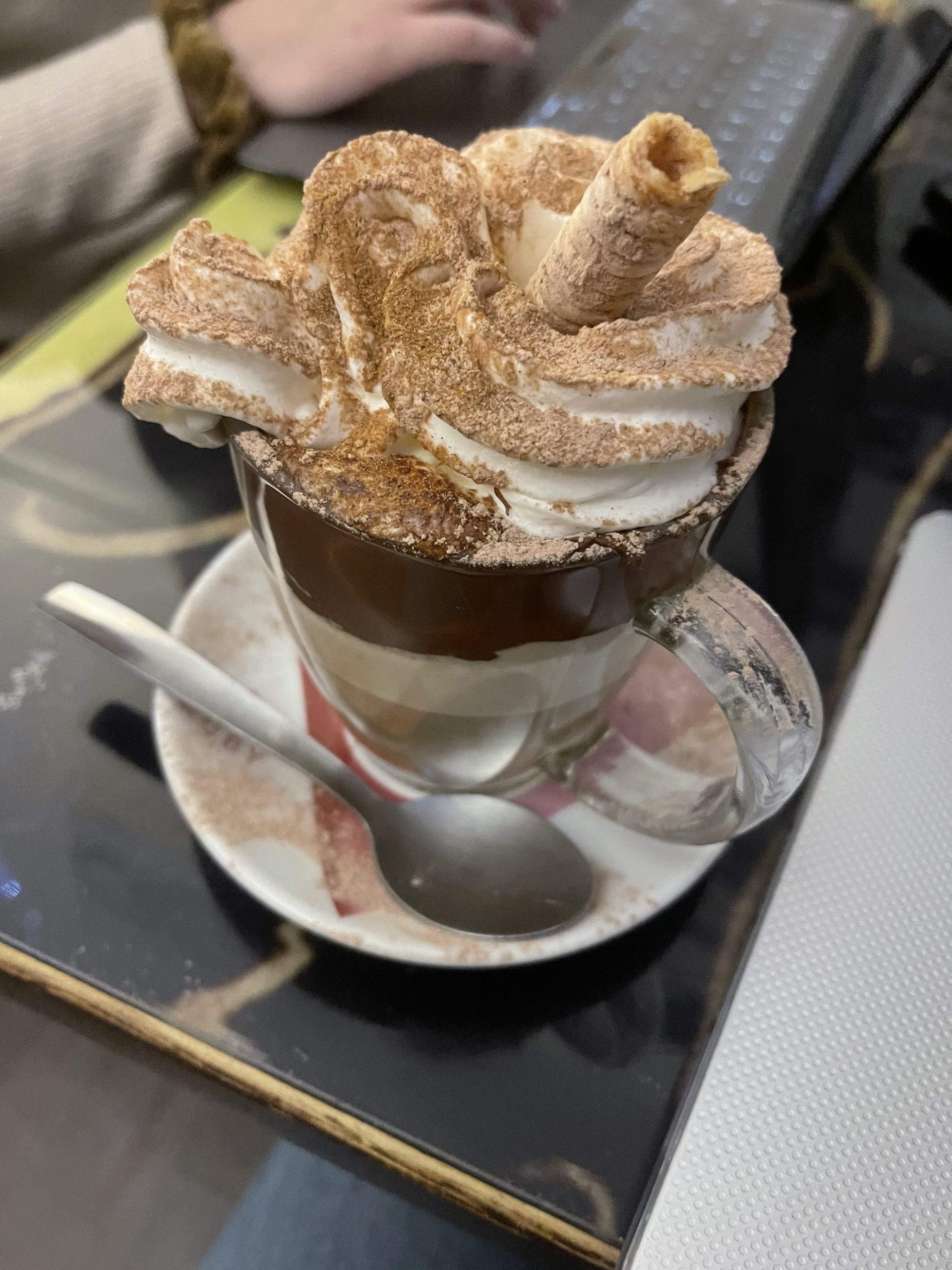 A picture of a cup of coffee with whipped cream and a candy straw.