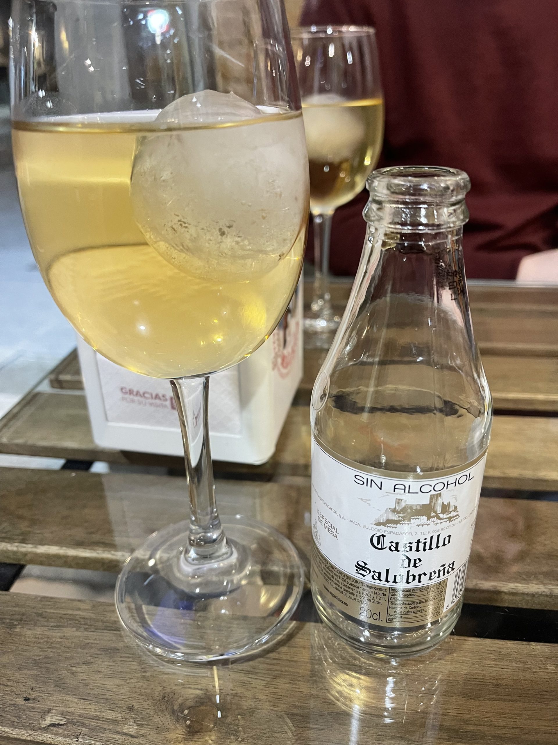 A picture of a wine glass full of liquid and an empty bottle next to it.