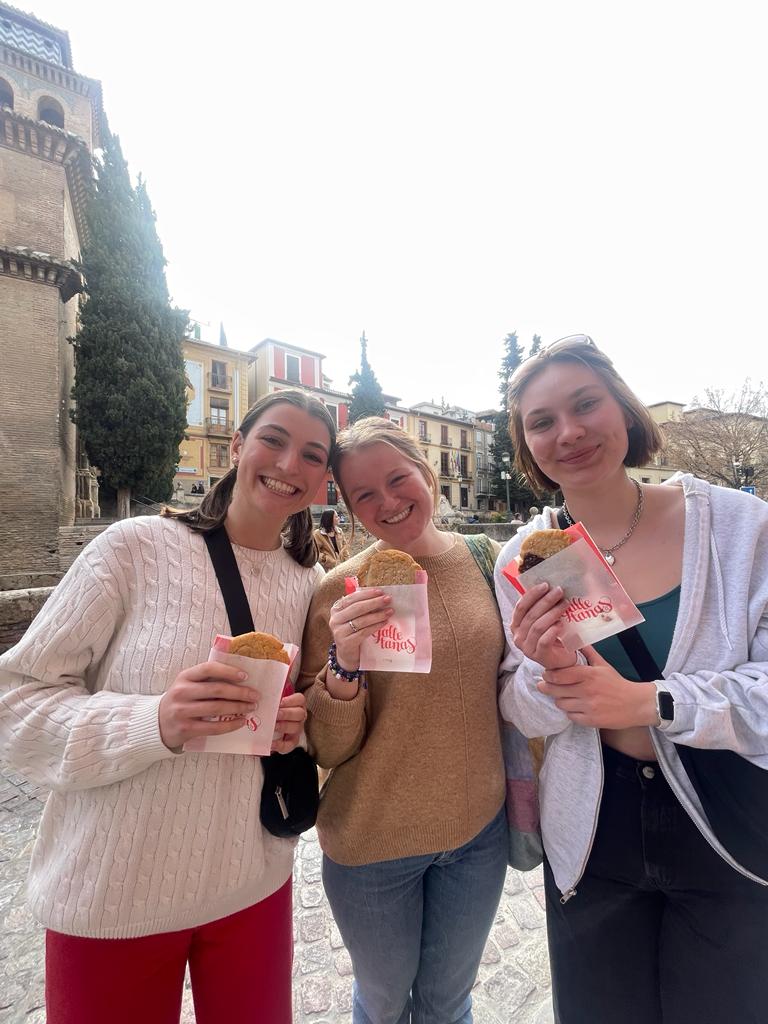 Three girls standing together holding cookies.